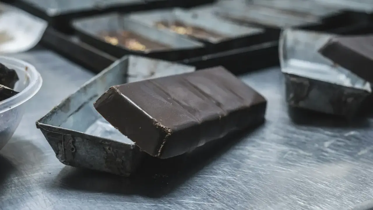 Une tablette de chocolat posée sur une petite boîte métallique. Idéal pour apprendre comment faire des copeaux de chocolat.