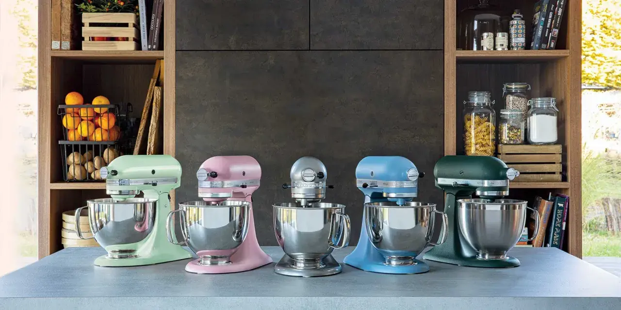 Cinq robots pâtissiers KitchenAid Classic ou Artisan de couleurs vives alignés sur un comptoir.