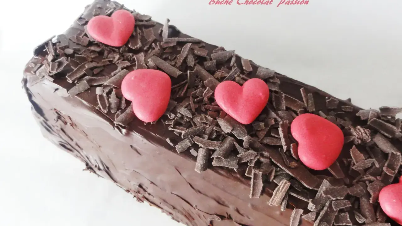 Bûche chocolat passion, un délice chocolaté orné de copeaux de chocolat et de cœurs rouges.
