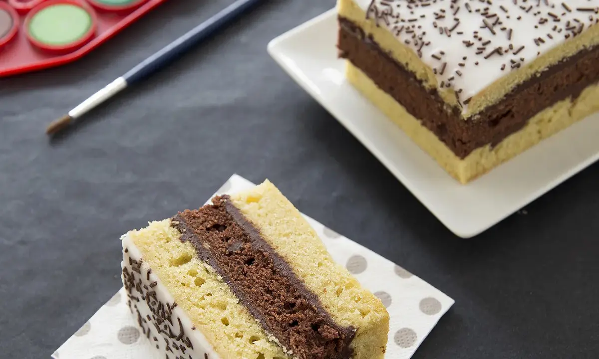 Une tranche de gâteau napolitain, digne du meilleur pâtissier, avec une palette de peinture et un pinceau.