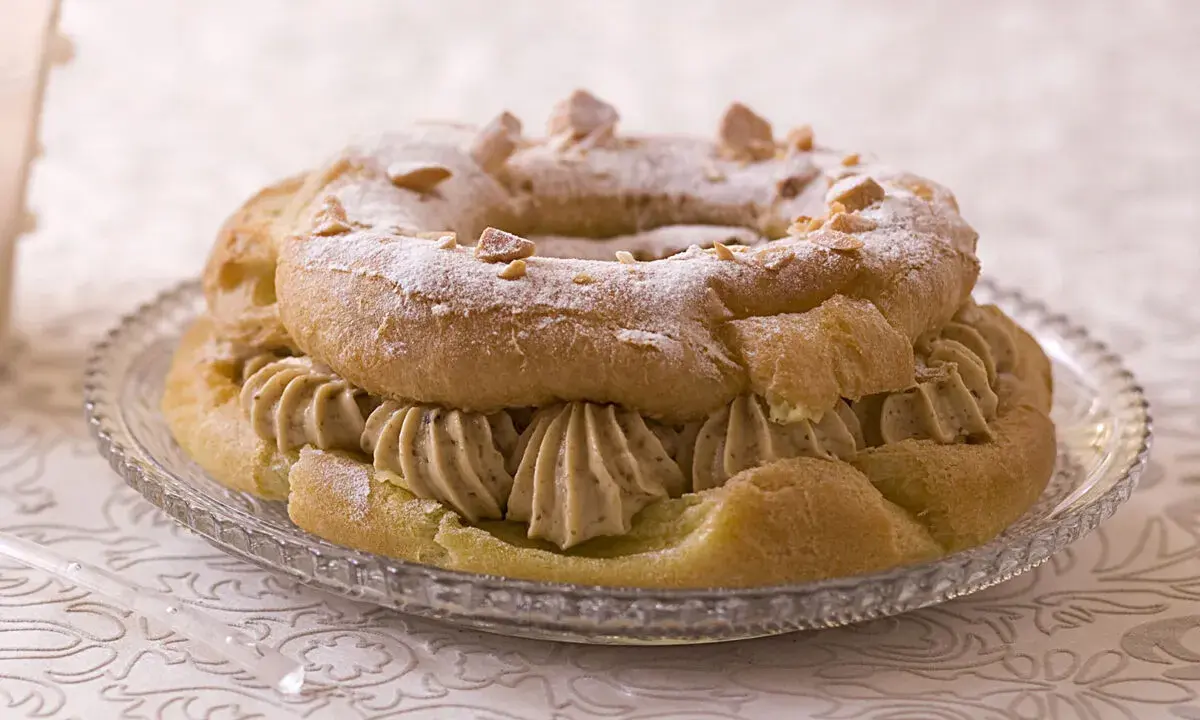 Un Paris-Brest généreusement garni de crème pâtissière au caramel beurre salé, saupoudré de sucre glace et d'amandes effilées.