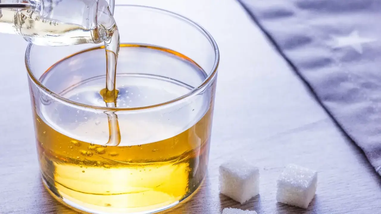 Versez le sirop de glucose dans un bol. Une recette simple pour des desserts parfaits. Trois morceaux de sucre à côté.