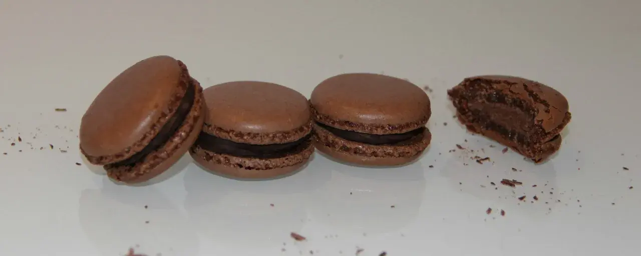 Trois macarons au chocolat et un croqué, parfaits pour une recette macaron chocolat.