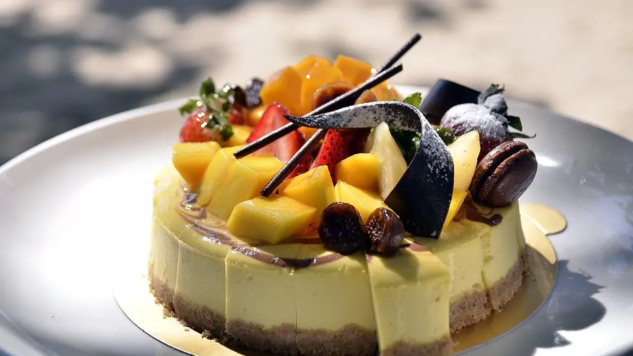 Gâteau crémeux sur un fond biscuit pour gâteau, garni de mangues, fraises, figues et chocolat.