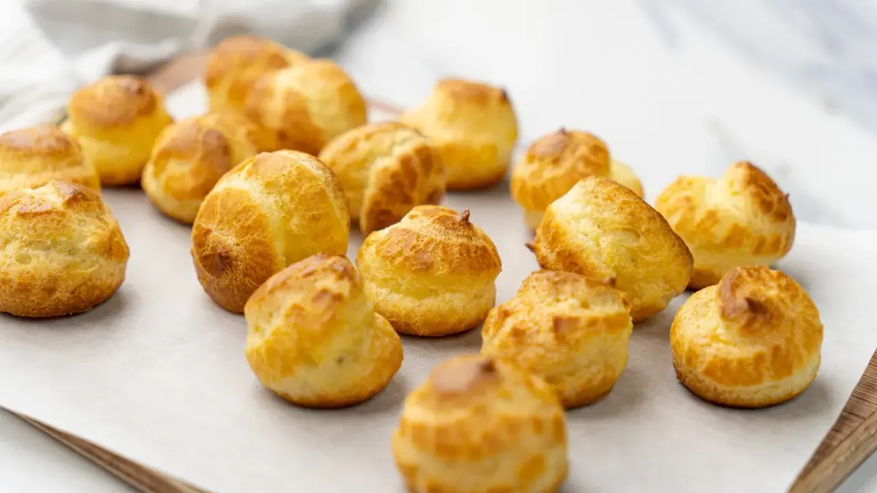 Une douzaine de choux pâtissiers dorés et gonflés, prêts à être dégustés.