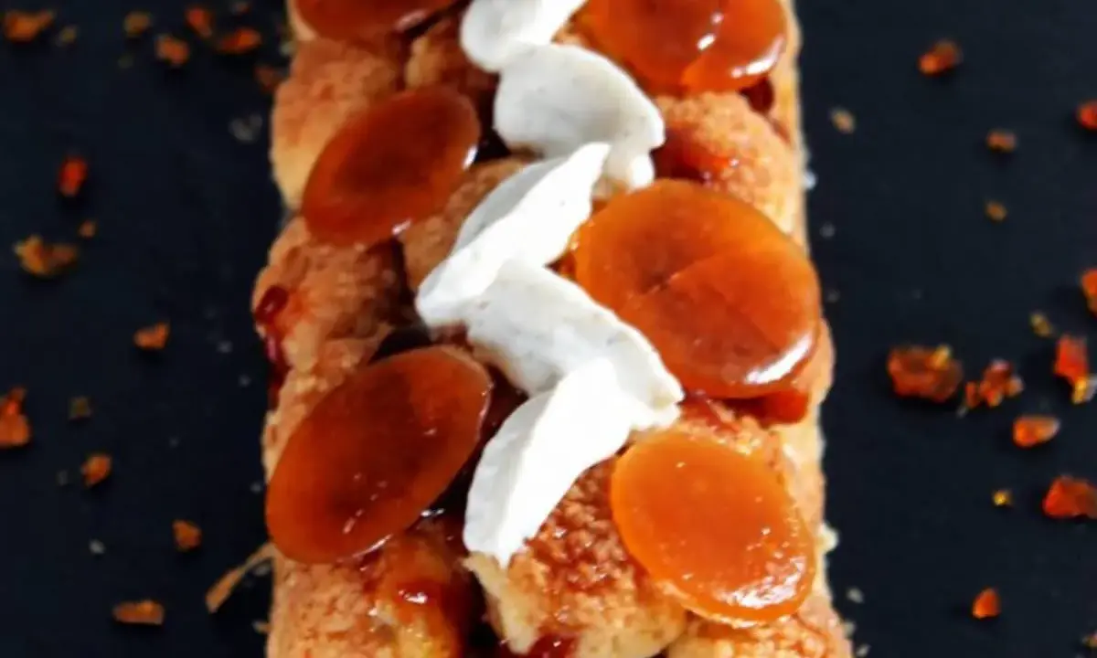 Bûche Saint Honoré gourmande, garnie de choux craquelins, crème onctueuse et éclats de caramel ambré. Un délice visuel et gustatif.