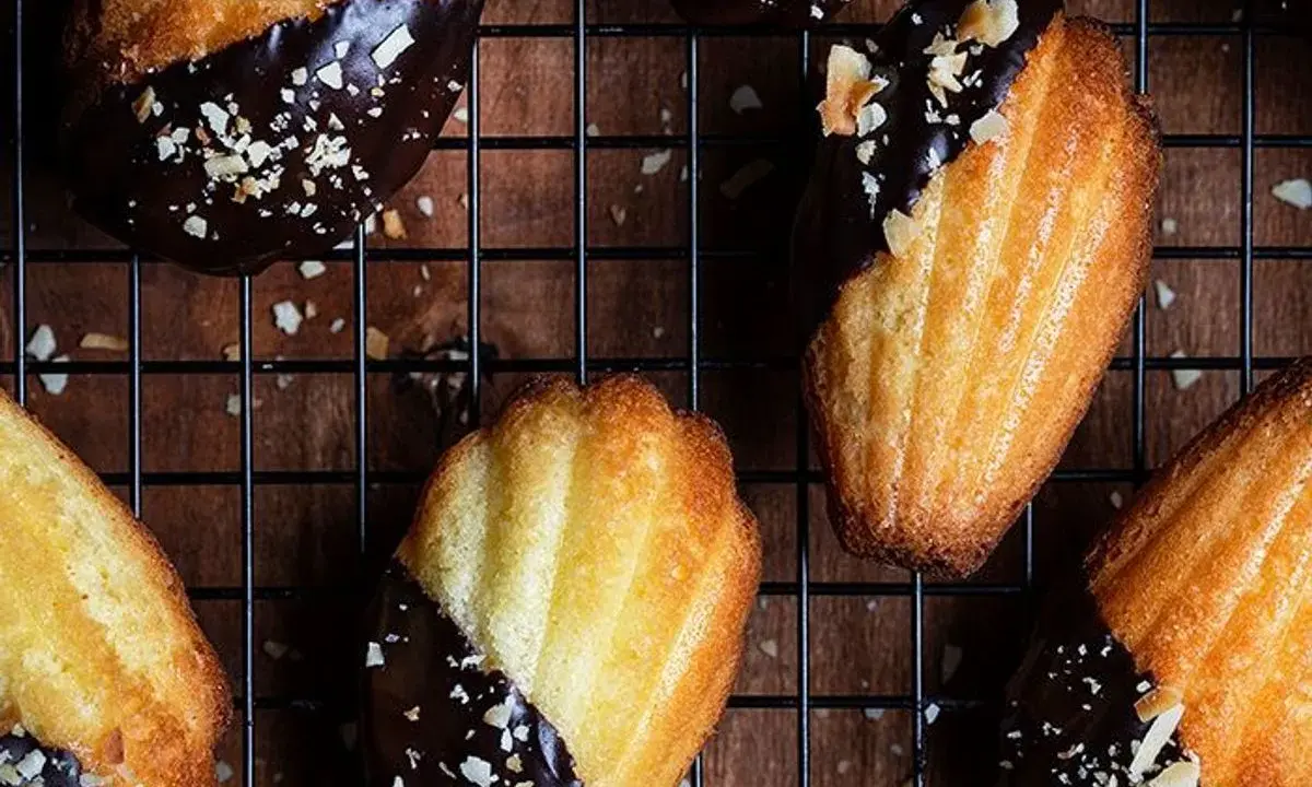 Des biscuits madeleine au chocolat, parsemés d'éclats d'amandes, refroidissent sur une grille. Un délice gourmand !