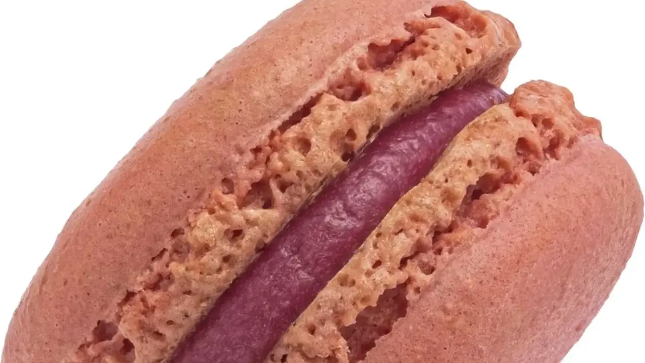 Un délicieux macaron framboise, avec sa coque rose pâle et sa ganache violette intense.