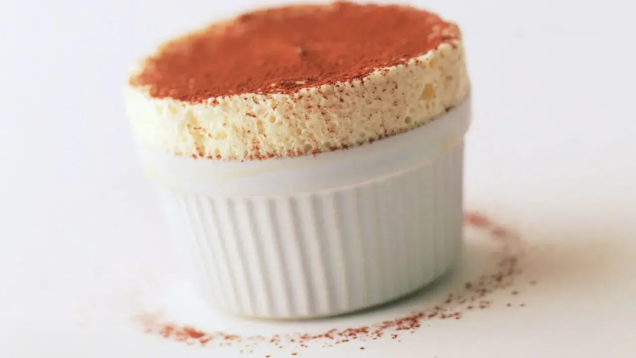 Un aérien soufflé au grand marnier, saupoudré de cacao, dans un ramequin blanc. Un délice léger et parfumé.