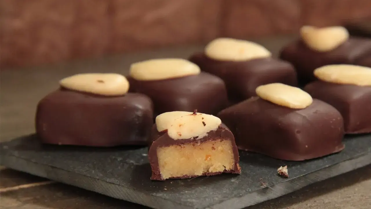 Délicieux bonbons au chocolat noir, garnis d'une pâte d'amande et surmontés d'une amande entière. Une recette gourmande à essayer !
