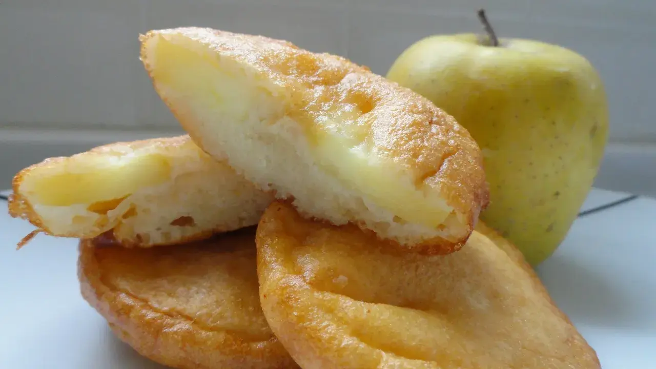Délicieux beignets aux pommes au four, dorés et moelleux, avec une pomme verte en arrière-plan. Parfait pour une recette gourmande.