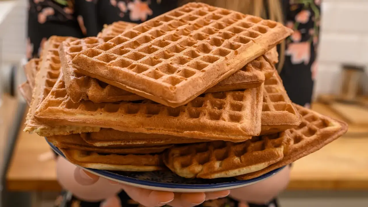 Une pile de gaufres dorées, prêtes à être dégustées. La pâte à gaufres a été cuite à la perfection, créant une texture croustillante à l'extérieur et moelleuse à l'intérieur.