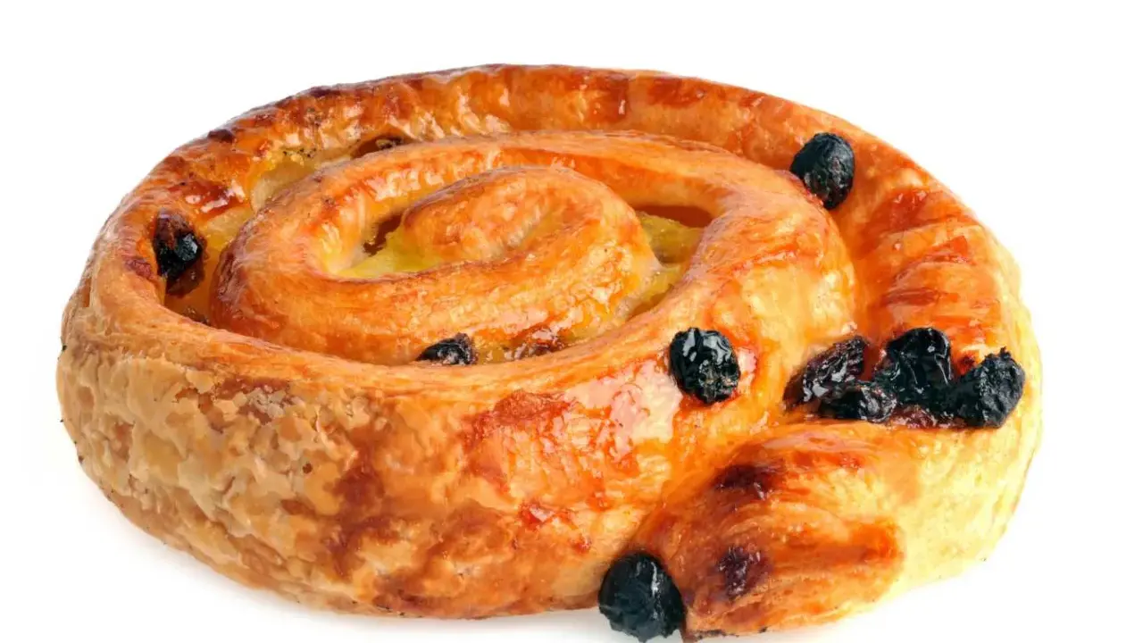 Un délicieux pain aux raisins, feuilleté et doré, parsemé de raisins secs moelleux.