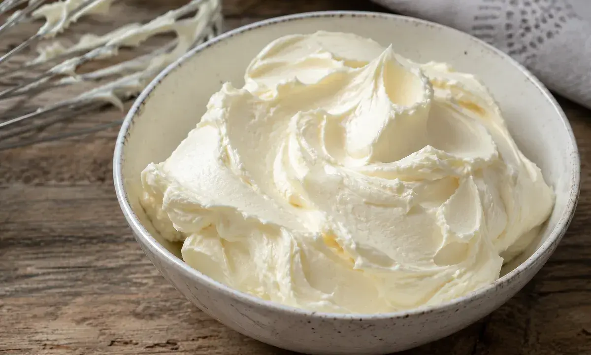 Un bol rempli de crème au beurre professionnelle, onctueuse et aérienne, prête à être utilisée pour des décorations pâtissières.