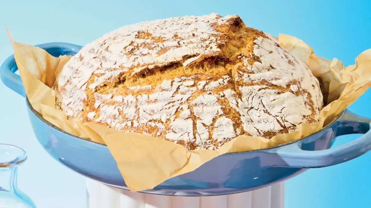Pain maison doré dans une cocotte bleue, prêt à être dégusté. Le temps de cuisson pain 500g est parfait pour cette croûte craquelée.
