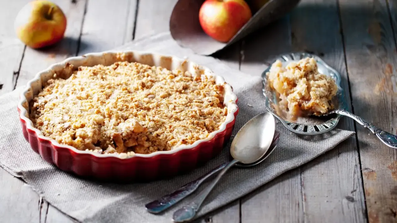 Un délicieux crumble aux pommes, avec sa pâte à crumble croustillante dorée, prêt à être dégusté.