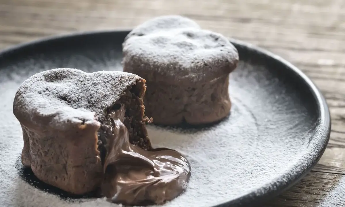 Deux coulants au chocolat inratables, saupoudrés de sucre glace, avec un cœur fondant qui déborde sur l'assiette.