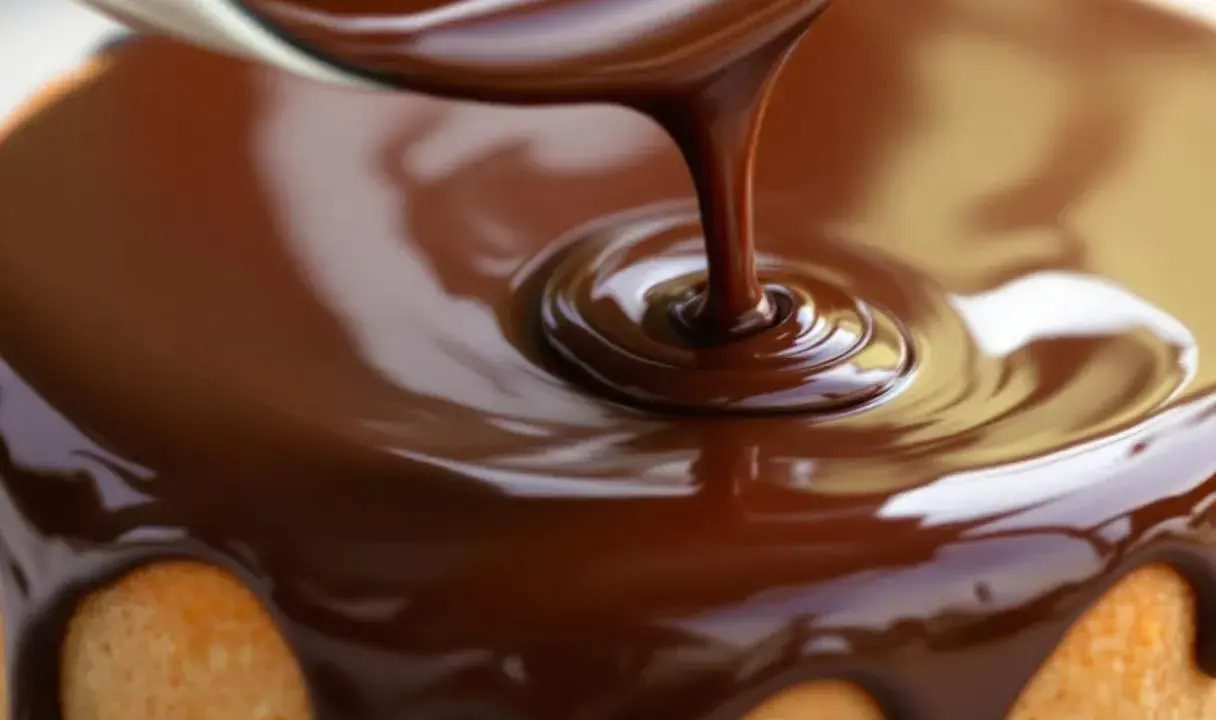 Un glaçage chocolat caramel coule sur un gâteau. La texture lisse et brillante promet un délice gourmand.