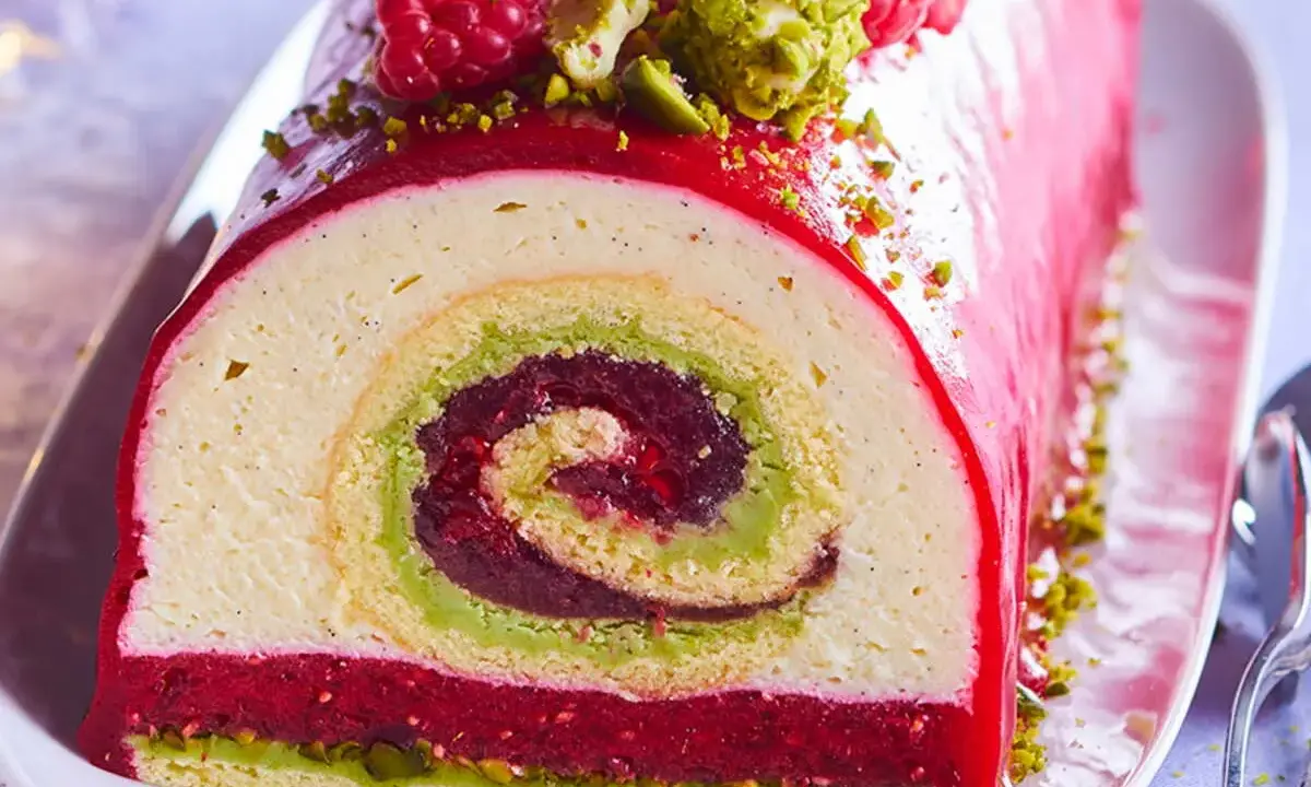 Bûche de Noël aux pistaches et framboises, un délice visuel et gustatif. La recette buche pistache framboise parfaite pour les fêtes.