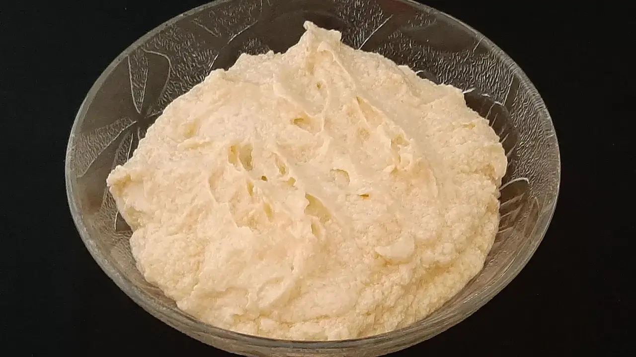 Crème d'amande onctueuse dans un bol en verre texturé, prête à être dégustée.