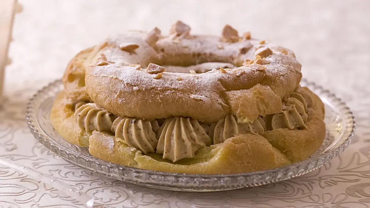 Bûche façon Paris-Brest, une couronne de pâte à choux garnie de crème onctueuse et saupoudrée de sucre glace et d'amandes effilées.