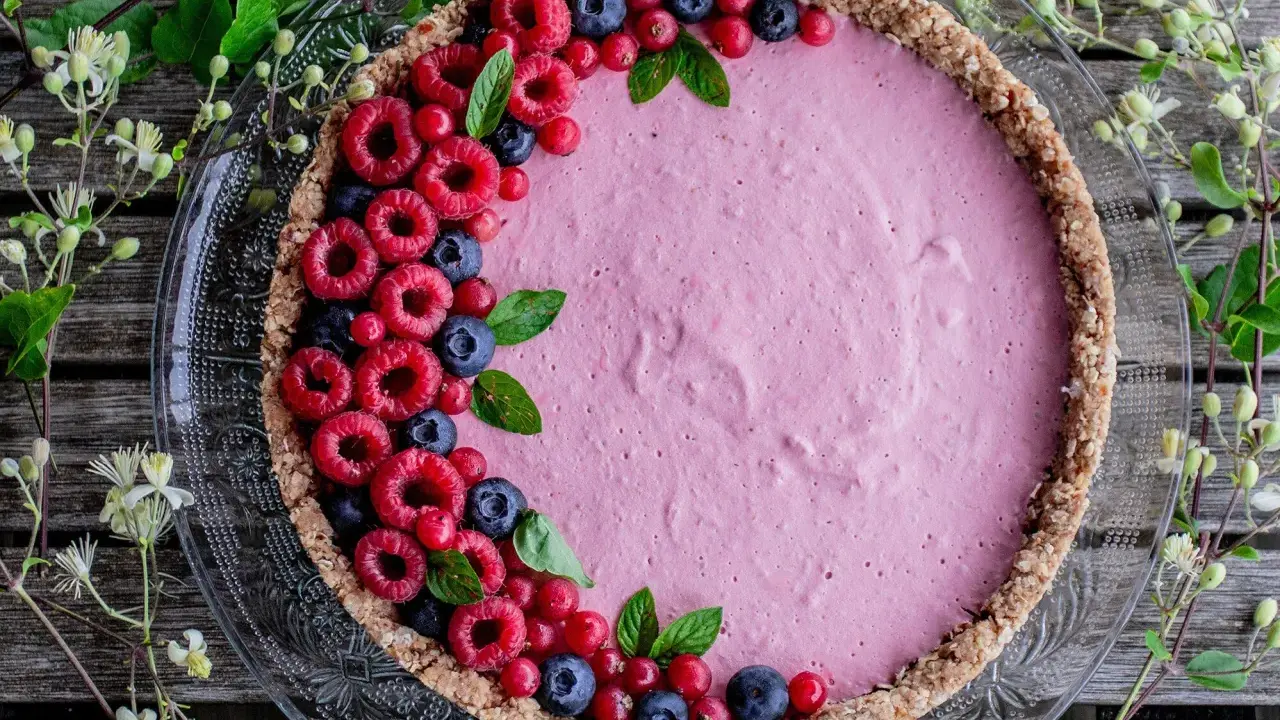 Délicieuse tarte aux fruits avec une garniture rose et des framboises, myrtilles et groseilles. La décoration tarte aux fruits est simple et élégante.