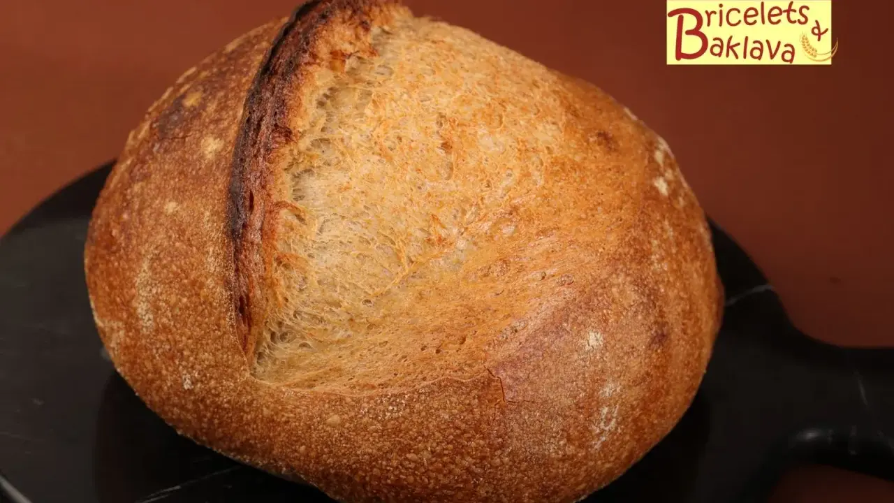 Belle miche de pain artisanal, prête après son temps de repos maximum. La croûte dorée et craquelée promet un délice.