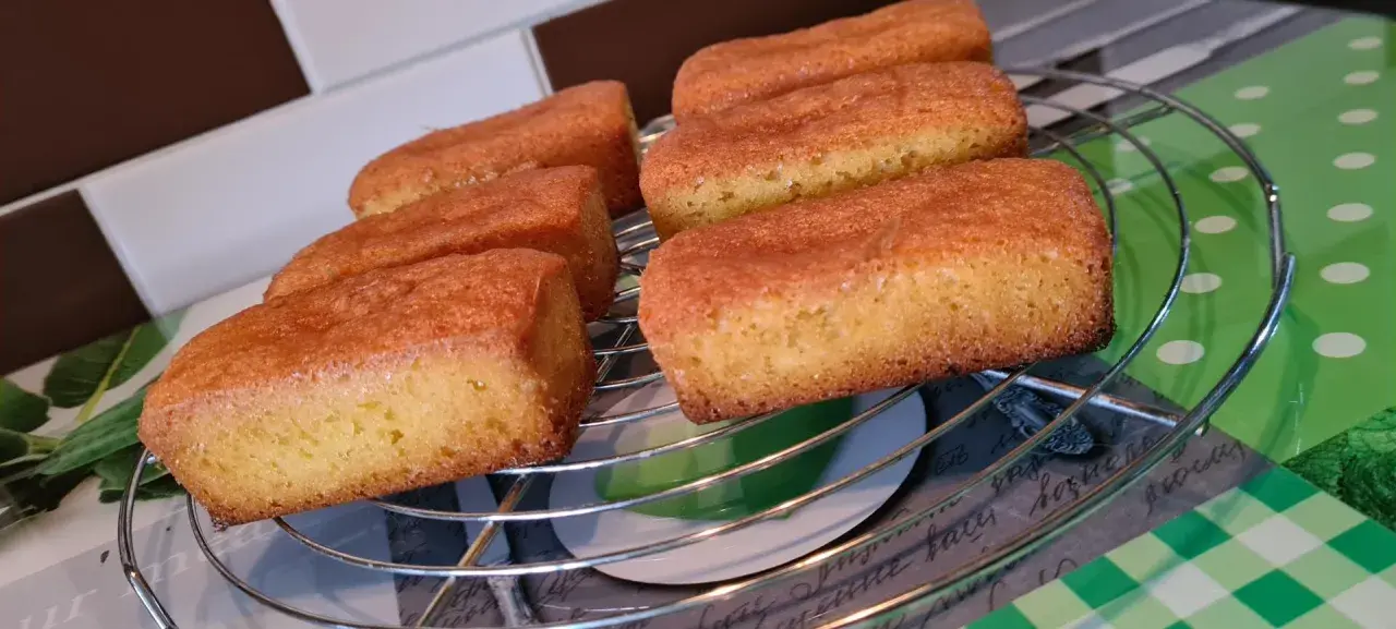 Six financiers dorés, des quatre quarts sans œuf, refroidissent sur une grille.