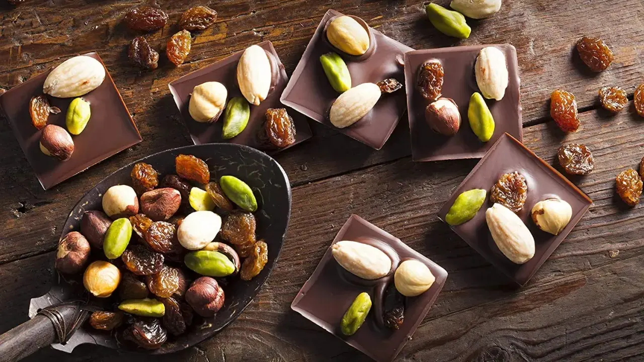 Carrés de chocolat noir Callebaut garnis d'amandes, noisettes, pistaches et raisins secs. Un délice à déguster !