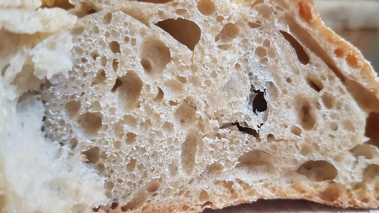 Gros trous dans le pain : astuces pour les éviter. La mie aérée et irrégulière d'une tranche de pain au levain.