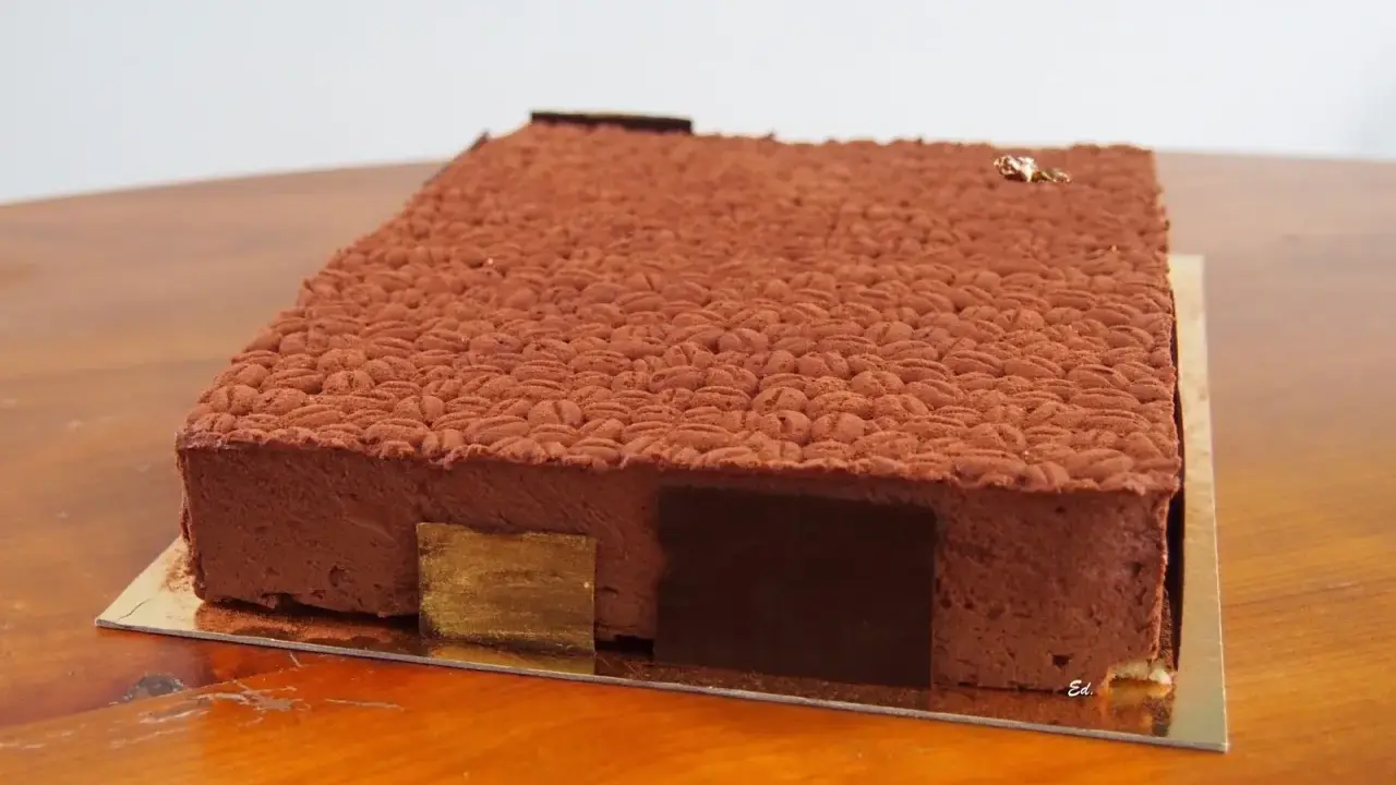 Gâteau rectangulaire au chocolat, décoré d'une texture rappelant des grains de café. Une recette insert crémeux café qui promet une dégustation exquise.