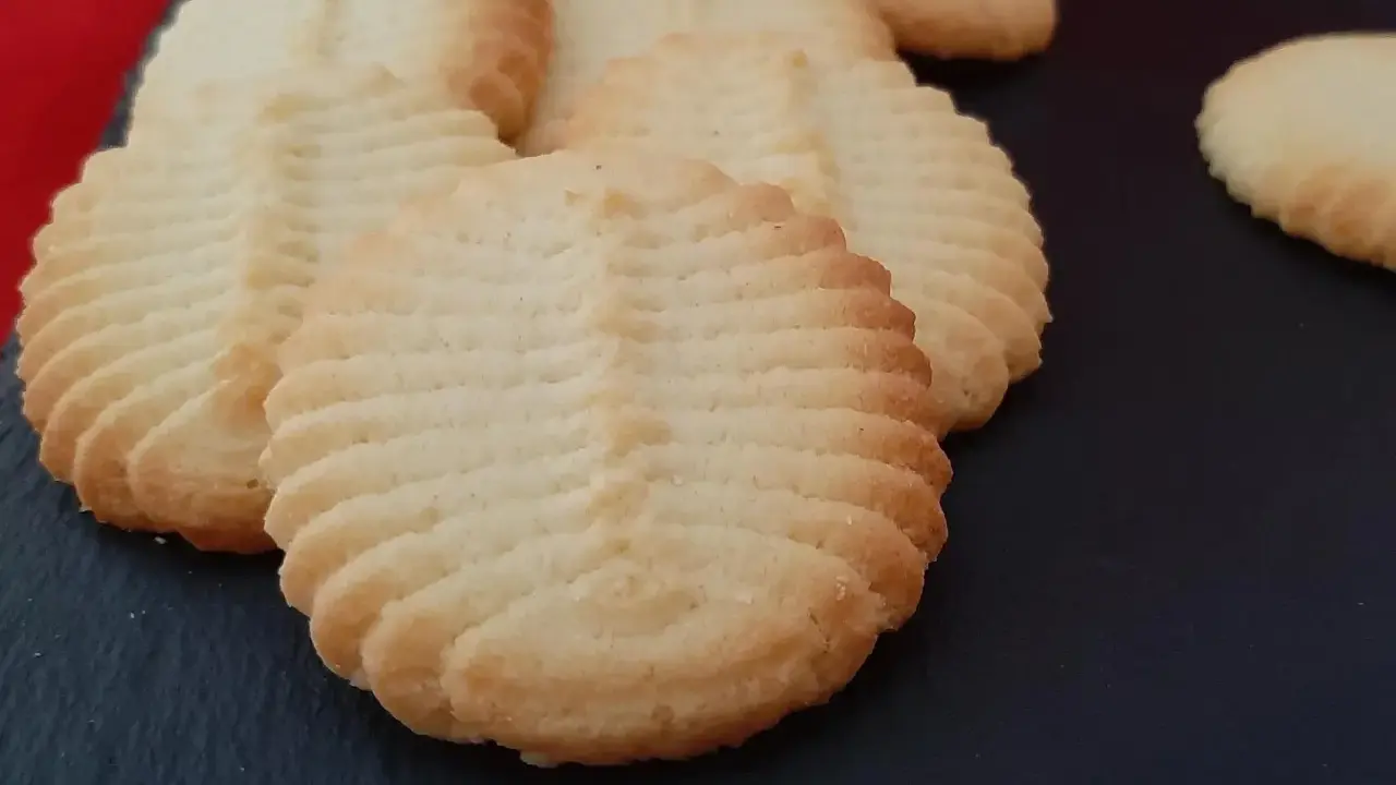 Un délicieux biscuit amande aux motifs striés, posé sur une surface sombre. Parfait pour accompagner un café.