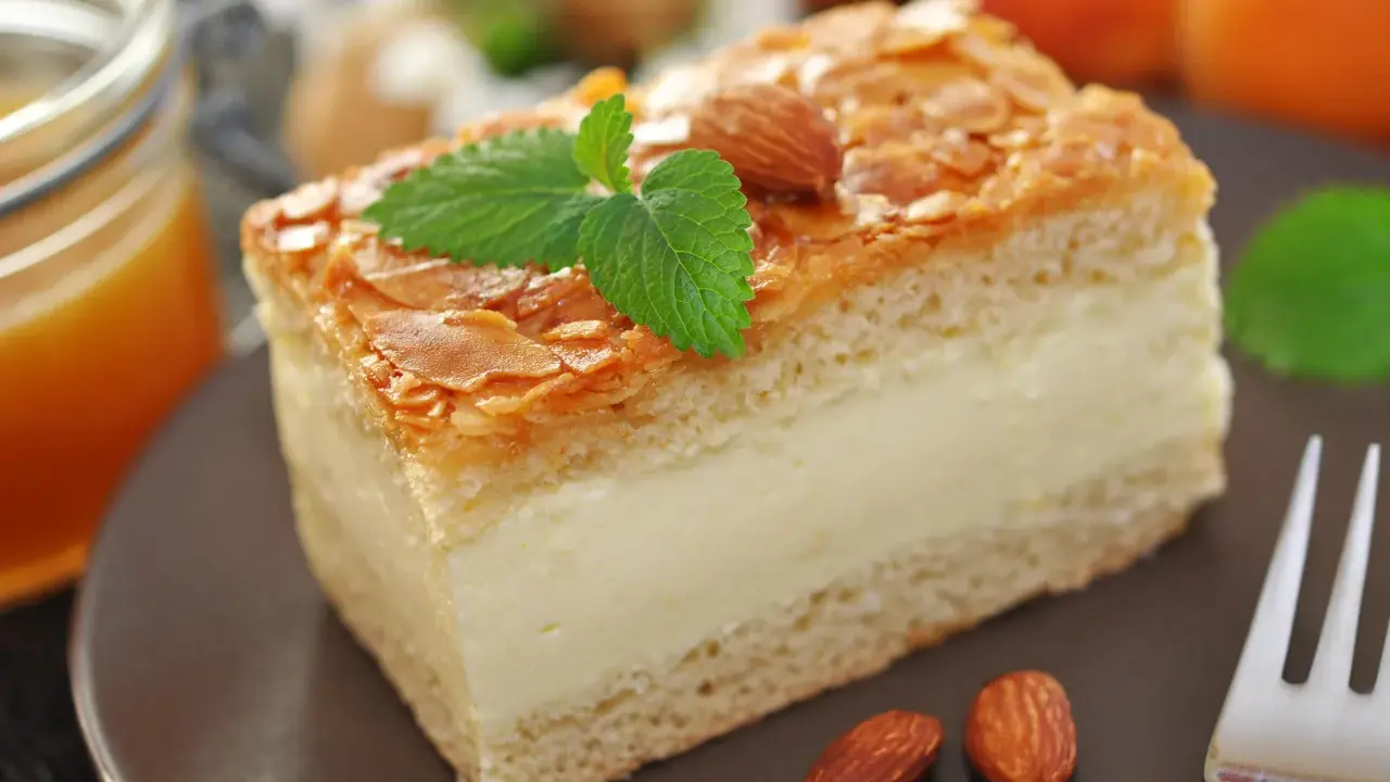 Gâteau nid d'abeille, une part crémeuse garnie d'amandes effilées et d'une touche de menthe. Parfait pour une recette gourmande.