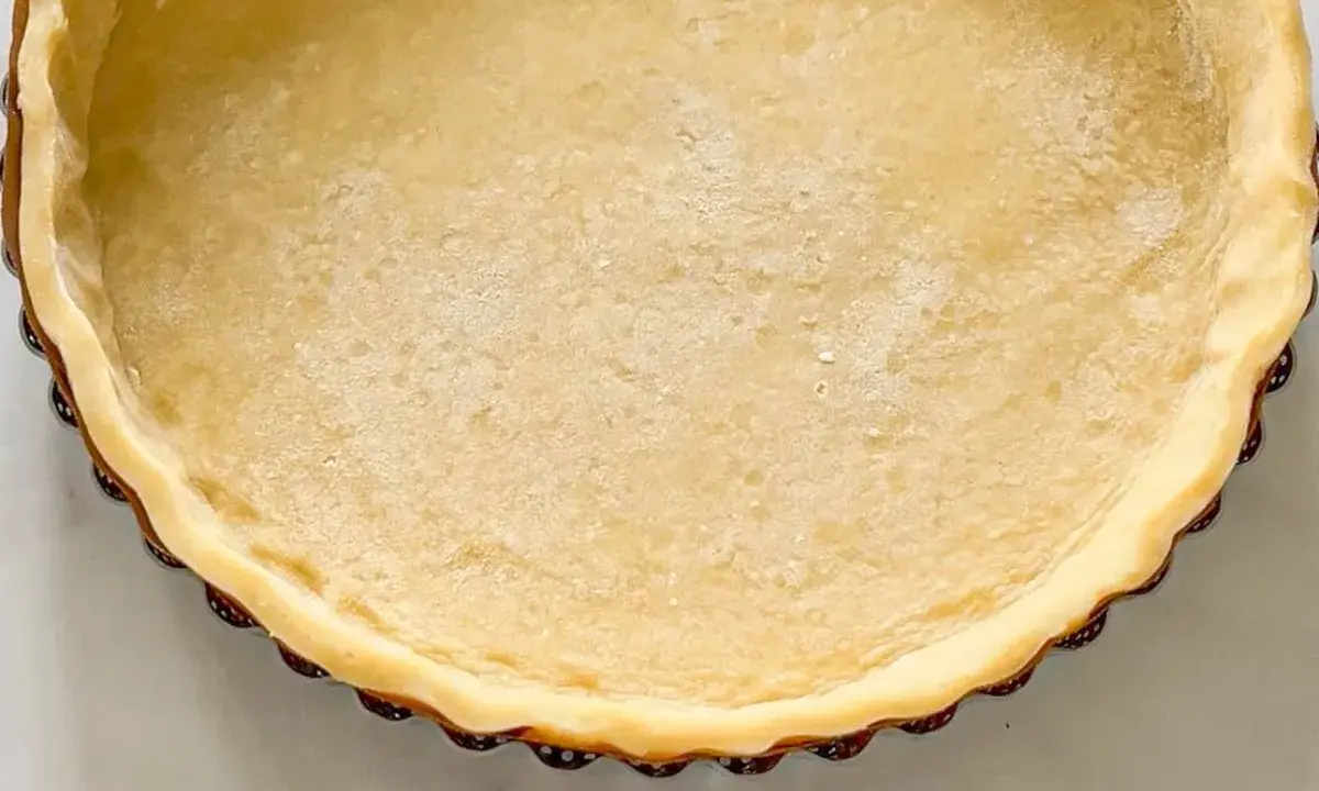 Une tartelette prête à être garnie, avec une belle pâte brisée à l'ancienne, dorée et légèrement farinée.