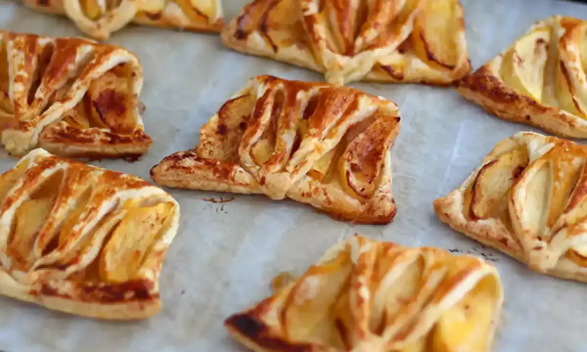 Plusieurs chaussons aux pommes dorés et feuilletés, prêts à être dégustés.