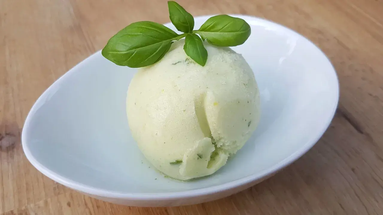 Une boule de sorbet citron vert et basilic, parfaite pour une recette sorbet citron professionnel. Délicatement garnie de feuilles de basilic frais.