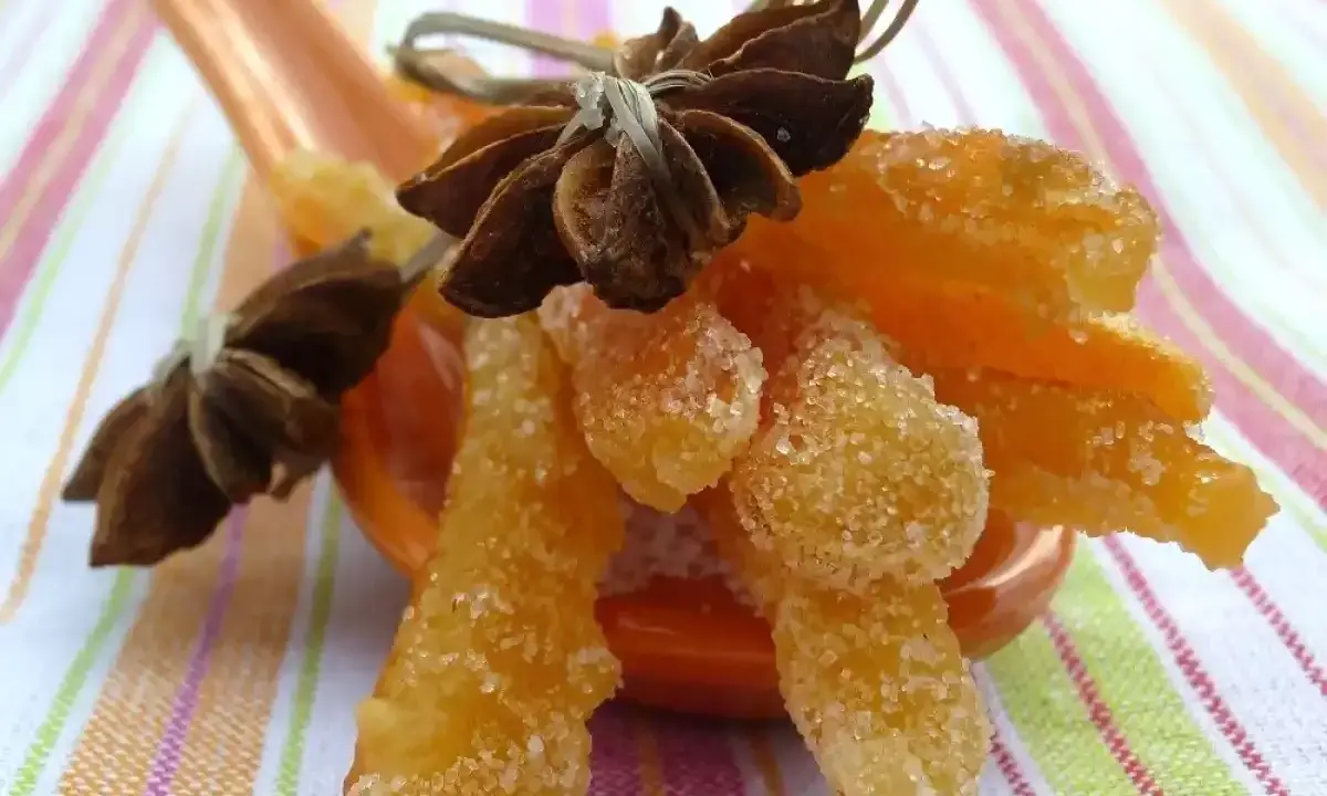 Oranges confites, une recette italienne gourmande, présentées sur une cuillère avec des étoiles de badiane.