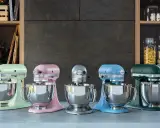 Cinq robots pâtissiers KitchenAid Classic ou Artisan de couleurs vives alignés sur un comptoir.