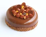 Entremet au chocolat avec un biscuit croustillant pour entremet, garni de rochers chocolatés, noisettes et dés de mangue.