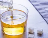 Versez le sirop de glucose dans un bol. Une recette simple pour des desserts parfaits. Trois morceaux de sucre à côté.