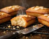 Financiers dorés, parfaits pour une recette traditionnelle. Vapeur s'échappant d'un gâteau à la texture aérée, garni d'amandes effilées.