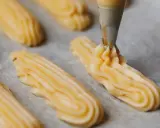Préparation de la pâte à choux pour la recette de maman choux à la crème. La poche à douille dépose des éclairs sur du papier cuisson.