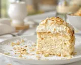 Tranche de gâteau aérien, une dacquoise amande légère, garnie de crème fouettée et d'amandes effilées grillées.