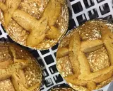 Trois pains au levain dorés, prêts pour la cuisson sur sole. Leurs croûtes craquelées et leurs incisions en croix promettent une texture parfaite.