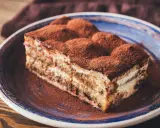 Tranche de tiramisu onctueux, saupoudrée de cacao, digne d'une recette tiramisu chef étoilé.