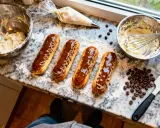 Quatre éclairs au café, garnis de crème et nappés de chocolat, sont prêts à être dégustés.