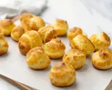 Une douzaine de choux pâtissiers dorés et gonflés, prêts à être dégustés.