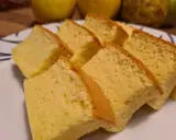 Tranches de moelleux gâteau japonais, léger et aérien, sur une assiette blanche. Des fruits jaunes sont flous en arrière-plan.