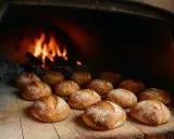 Des pains dorés attendent leur temps de cuisson du pain au four, avec des flammes vives en arrière-plan.