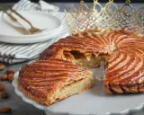 Galette des Rois dorée, garnie d'une généreuse crème d'amande. Une part est coupée, révélant sa texture feuilletée.
